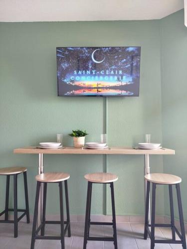 - une table avec quatre tabourets et une télévision murale dans l'établissement Charmant T2 neuf climatisé, vue sur les quais, à Sète