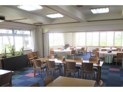 uma sala de jantar com mesas, cadeiras e janelas em Kikai Daiichi Hotel - Vacation STAY 30444v 
