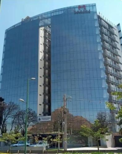 a large glass building with a reflection of a building at Hermoso Garzonier in Cochabamba