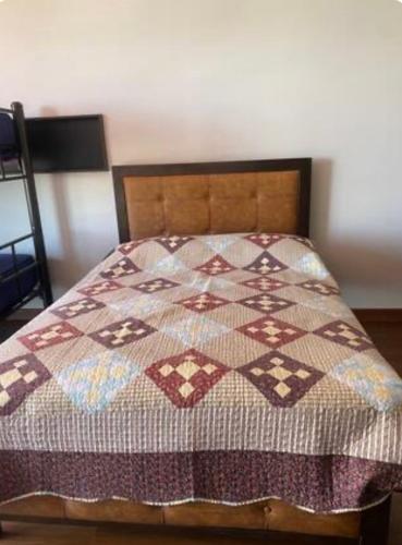 a bed with a quilt on it in a bedroom at Hermoso Garzonier in Cochabamba