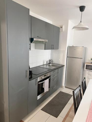 une cuisine avec un réfrigérateur en acier inoxydable et un évier dans l'établissement Appart Charme Contemporain et Balcon Verdoyant à Bois-Colombes, à Bois-Colombes