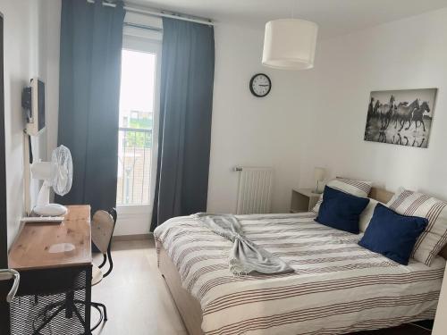 - une chambre avec un lit, une table et une horloge dans l'établissement Appart Charme Contemporain et Balcon Verdoyant à Bois-Colombes, à Bois-Colombes