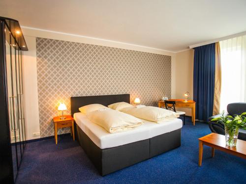1 dormitorio con 1 cama con 2 mesas y 2 lámparas en Ahauser Land & Golfhotel, en Alstätte