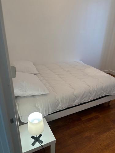 a bed with a white blanket and a side table at Appartement des merveilles in Vénissieux