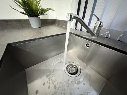 a kitchen sink with water running from a faucet at Cosy Chic Flat in the Heart of Kidderminster in Kidderminster