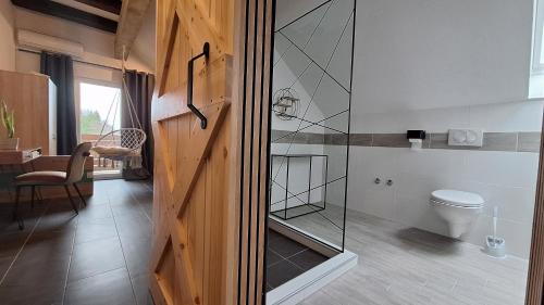 een badkamer met een toilet en een glazen douchedeur bij O'Toole's, Plitvice in Korenica