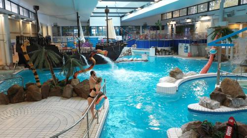 two people in a water slide in a swimming pool at StayViva - Spacoius 3 BR House - Garden, Games Room, Parking near Town Centre and Train station in Bracknell