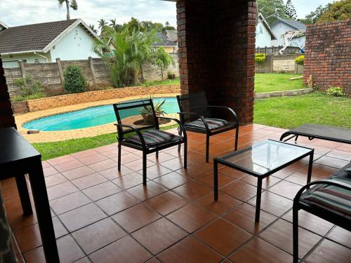 um pátio com 4 cadeiras, uma mesa e uma piscina em Zinoma guest house em Empangeni