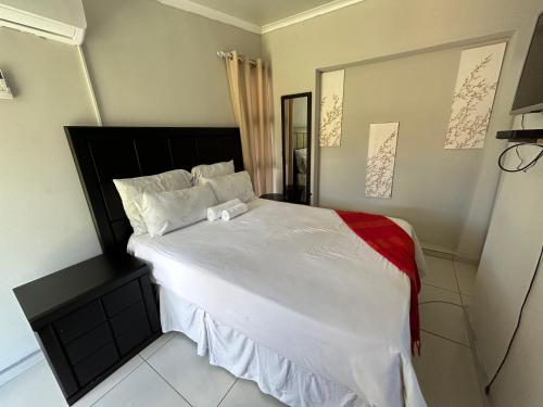 um quarto com uma cama grande e lençóis brancos em Zinoma guest house em Empangeni