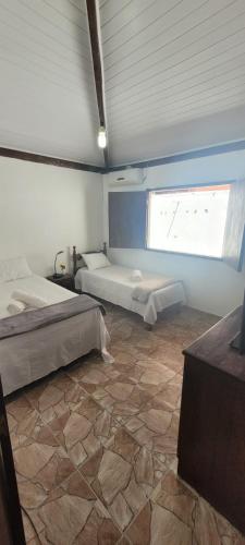 Cette grande chambre comprend deux lits et une fenêtre. dans l'établissement Casa Recanto Coqueiral, à Porto Seguro