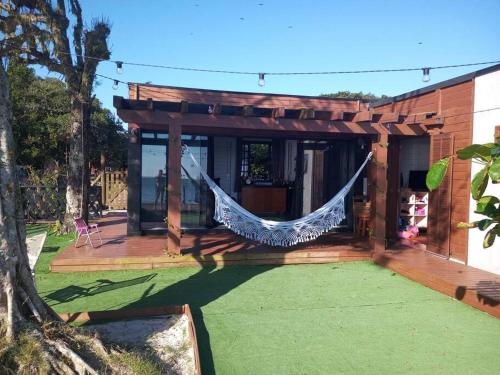 a hammock hanging from a porch of a house at Hygge Sunset House in Ilha do Mel
