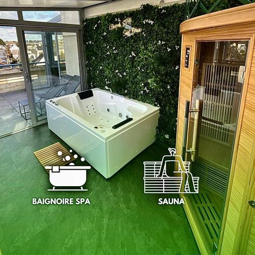 une baignoire assise sur une terrasse avec un sol vert dans l'établissement L’Escapade SPA Sauna + Jacuzzi, à Saint-Brieuc