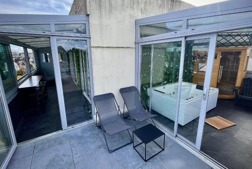 a patio with two chairs and a bath tub at L’Escapade SPA Sauna + Jacuzzi in Saint-Brieuc