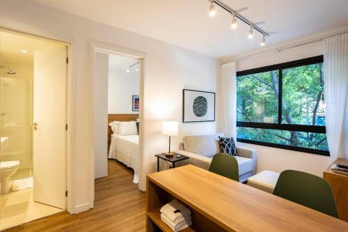 a living room with a bed and a desk in a room at Boulevard Ibirapuera in São Paulo