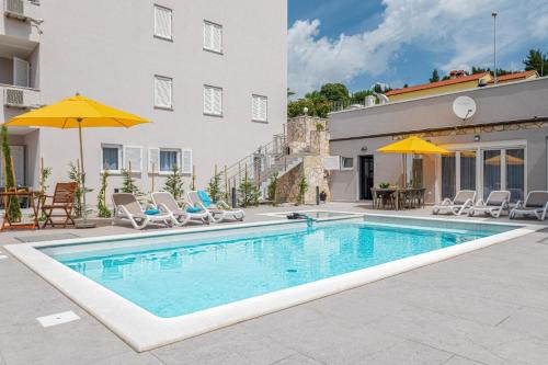 a swimming pool with chairs and umbrellas next to a building at Ferienhaus in Rabac mit beheizbarem Privatpool für 5 Personen in Rabac