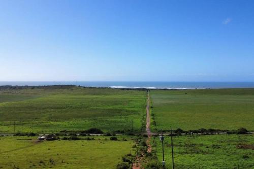 a road in a field with the ocean in the background at The Farmstead in Cannon Rocks