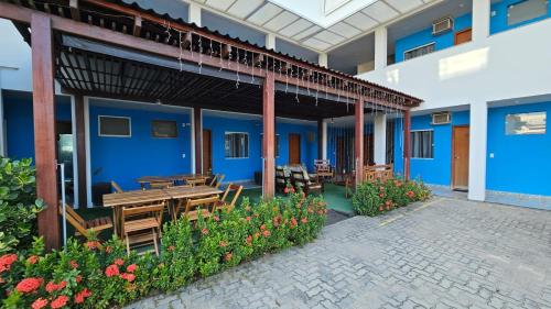 un patio con mesa de madera, bancos y flores en POMMER POUSADA en Guriri