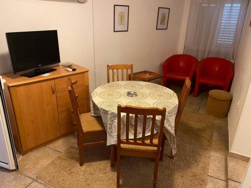 een eetkamer met een tafel en stoelen en een televisie bij Apartmani Nedic in Petrovac na Moru