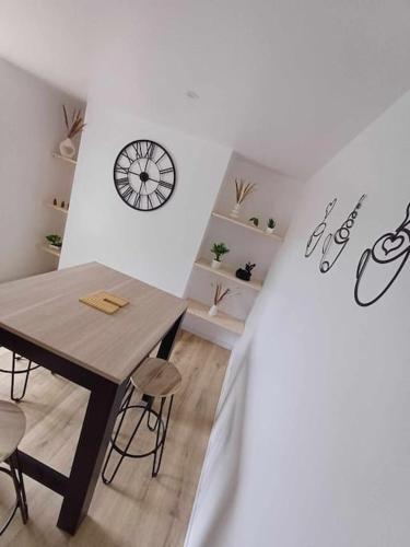une chambre avec une table, des chaises et une horloge dans l'établissement Agréable maison neuve, à Pontivy