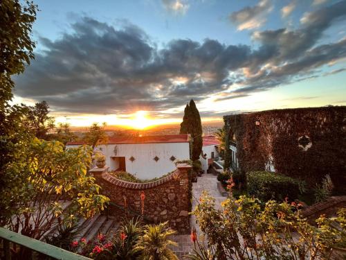 a sunset over a building with the sun setting at Hotel Posada la Ermita in San Miguel de Allende