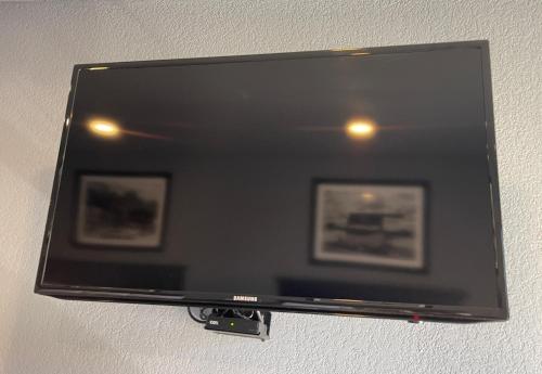 a flat screen tv on a wall with two pictures at Interstate Inn in Roland