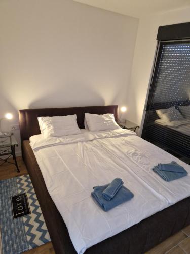 a bed with two blue towels on top of it at Apartmani Relaxsea in Privlaka