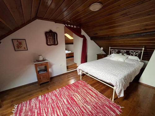 a bedroom with a bed and a red rug at Casa do largo in Casais do Chão da Mendiga