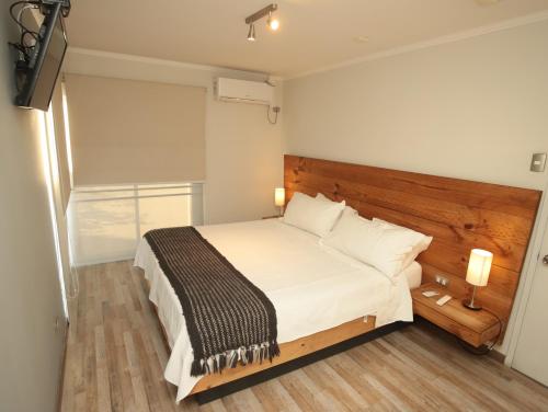 a bedroom with a white bed with a wooden headboard at De Triana Hotel in Rancagua