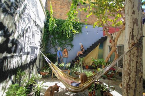 una donna seduta su un'amaca in un giardino di Art House Hostel Guadalajara a Guadalajara