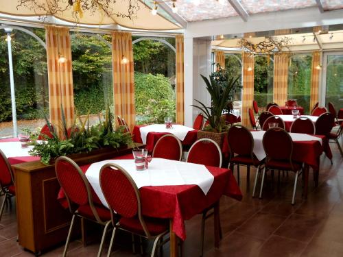 a dining room with tables and chairs and windows at Hotel-Garni Herzog in Loher Ostmark