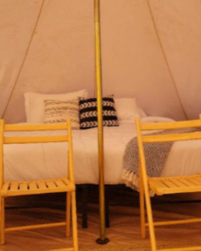a bedroom with a bed and two chairs in a tent at Olympic Glamping in Port Angeles