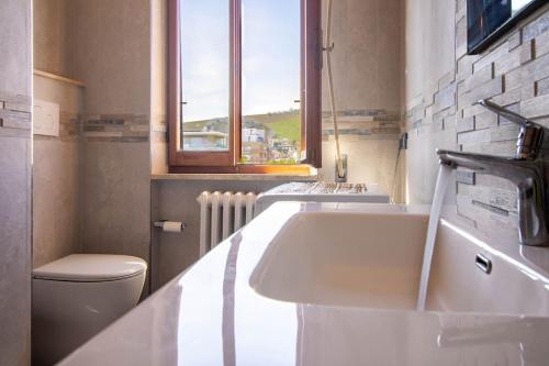 ein Bad mit einem Waschbecken, einem WC und einem Fenster in der Unterkunft [Dimora Fronte Mare] Wi-Fi 7 posti Parcheggio in Porto San Giorgio
