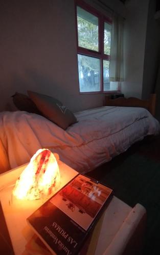 Un dormitorio con una cama y una mesa con un libro en Hogar cerca del aeropuerto en Ushuaia