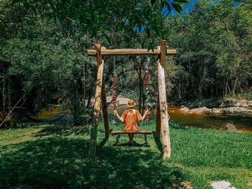 a statue of a person sitting on a swing at Suíte com cachoeira no quintal in Antônio Carlos