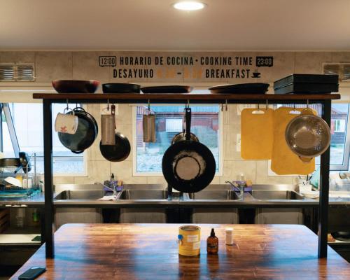 a kitchen with pots and pans hanging from a shelf at Folk Hostel in El Calafate