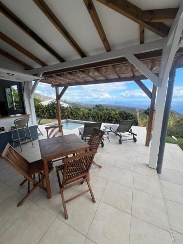 a patio with a table and chairs and a view at Kaz Karaîb' in Fond Belle Fontaine