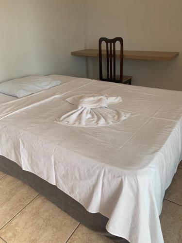a white blanket on a bed with a chair at Dulc in Ribeirão Preto