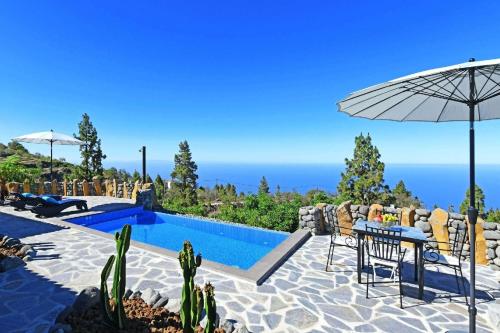 een villa met een zwembad en een tafel met een parasol bij Ferienhaus mit Privatpool für 4 Personen ca 85 qm in Tijarafe, La Palma Westküste von La Palma in Tijarafe