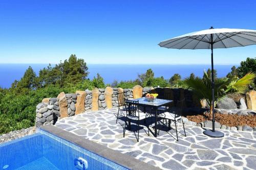 een tafel en stoelen met een parasol naast een zwembad bij Ferienhaus mit Privatpool für 4 Personen ca 85 qm in Tijarafe, La Palma Westküste von La Palma in Tijarafe