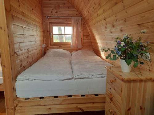 a bed in a wooden cabin with a window at 42 Camping Pod in Silberstedt