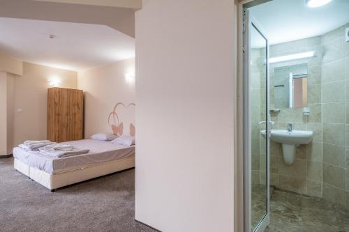 1 dormitorio con cama, ducha y lavamanos en Yubim rooms & free private parking en Sofía