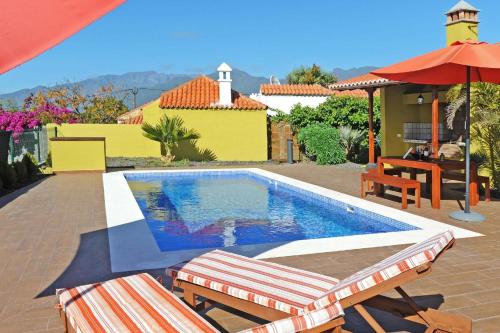 a swimming pool with two chairs and an umbrella at Ferienhaus mit Privatpool für 6 Personen ca 108 qm in Las Manchas, La Palma Westküste von La Palma in Puerto Naos
