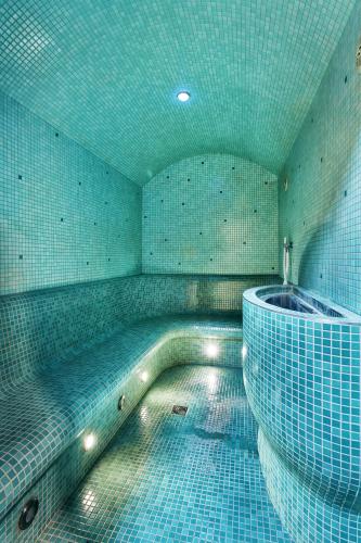 a bathroom with a tub and a tiled wall at Vienna House Easy by Wyndham Pilsen in Plzeň