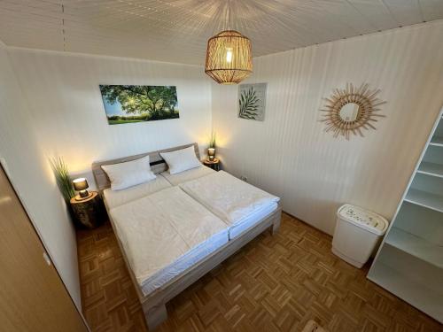 Habitación pequeña con cama y lámpara de araña. en Moderne Ferienwohnung mit kostenlosem Eintritt zum Freibad, en Falkenstein