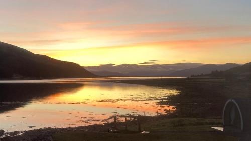 a sunset over a body of water with mountains at Sunset POD in Dunan