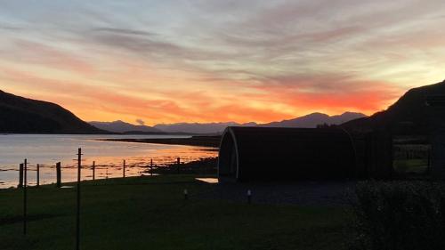 a sunset over a body of water with mountains at Sunset POD in Dunan