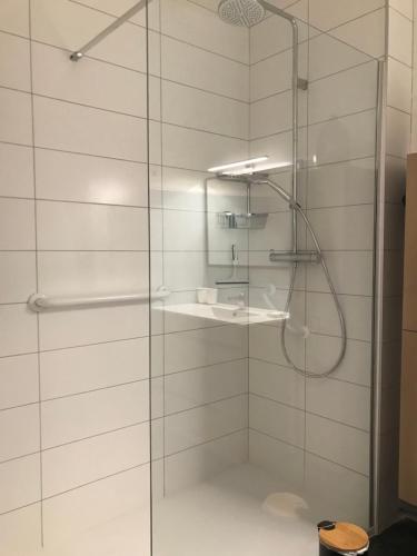 d'une douche avec une porte en verre et un lavabo. dans l'établissement LE DOUMER - 3 étoiles - Garage - Gare - HyperCentre, à Vichy