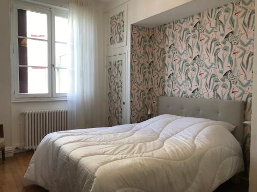 une chambre avec un lit avec un papier peint fleuri dans l'établissement LE DOUMER - 3 étoiles - Garage - Gare - HyperCentre, à Vichy
