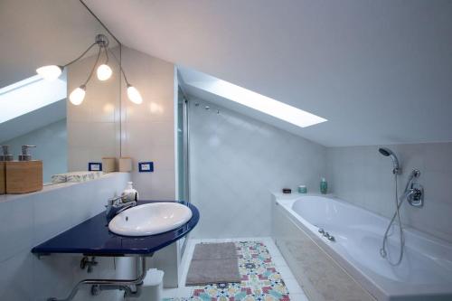 un bagno bianco con lavandino e vasca di [Terrazzino Vista Mare] Idromassaggio Wi-Fi A/C a Porto San Giorgio
