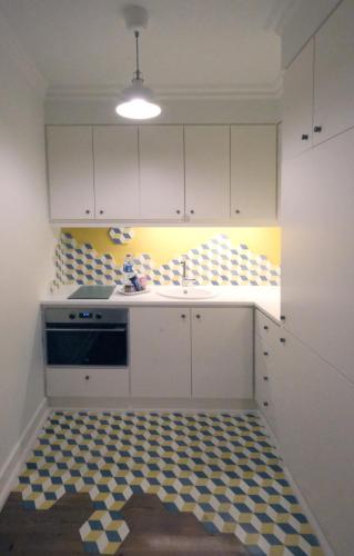 a kitchen with white cabinets and a checkered floor at Apartamentos Ázera - António Ázera in Praia da Vitória